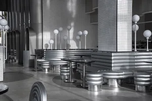 A sleek, industrial restaurant interior with metallic seating and tables.