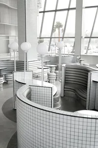 Modern restaurant interior with white grid tiles on walls and curved benches