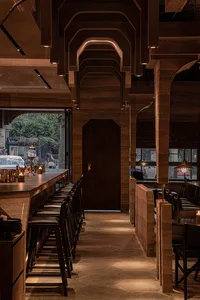 Modern restaurant interior with wooden decor and seating.
