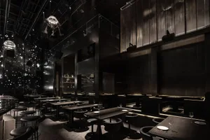 Industrial-style restaurant and bar interior featuring metal, glass, and concrete materials.