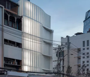 The exterior of a modern office building with a metal-cladding facade, featuring a sleek, minimalist design.