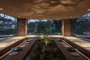 Industrial-style spa interior with terrazzo and brick elements, featuring a central water feature and seating areas.