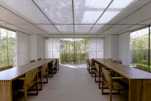 A minimalist workspace with wooden tables and glass walls, featuring a modern design.