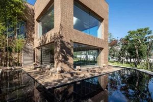 Modern building constructed with brick, featuring large glass windows and a reflection pool.
