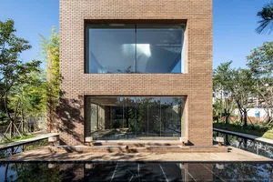 Modern brick building with large glass windows and a peaceful outdoor setting.