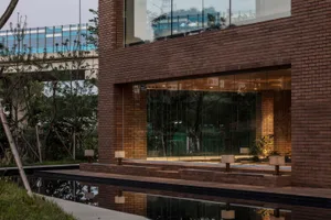 Modern residential exterior with brick cladding and large glass windows reflecting the surrounding environment.