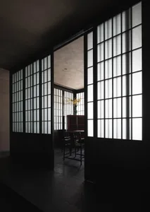 A minimalist room featuring white windows, wooden flooring, and simple furniture.