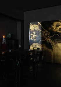 A modern dining room featuring metal furniture and intricate artwork with a flower and dragon motif.