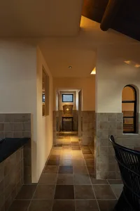 A hallway with tile flooring and concrete walls, showcasing spatial composition in interior design.
