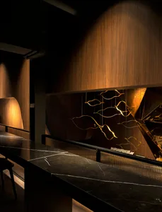 Modern bar area featuring a sleek black marble counter with golden lighting and wooden accents.