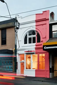 粉白雙色店面，設有大型拱形窗戶與室內燈光。