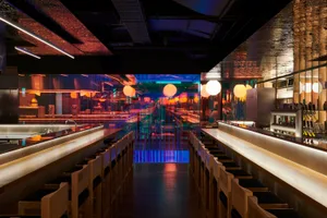 Modern minimalist restaurant with wooden seating, glass walls, and neon lights.
