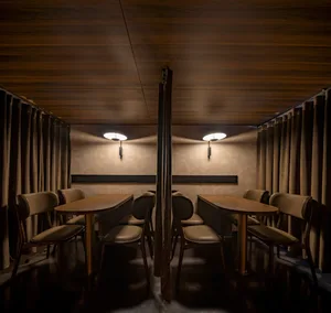 Restaurant interior with wooden walls, leather seating, and fabric curtains