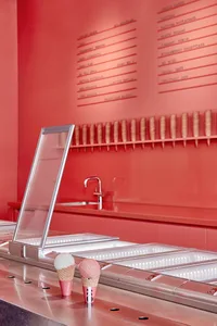 A modern restaurant interior with a sleek metallic counter top featuring an ice cream display and menu behind it.