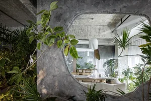 Industrial cafe interior with concrete walls and plants.