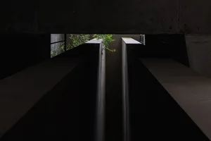 A dark, minimalist concrete interior with a black background and water-like features.