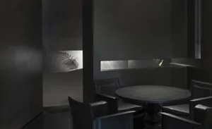A modern black metal restaurant interior with a round table, chairs, and metallic accents.