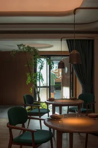 A cozy cafe interior with wooden tables and chairs, plants, and warm lighting.