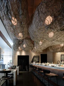 A modern industrial cafe interior featuring a ceiling made of crumpled paper.