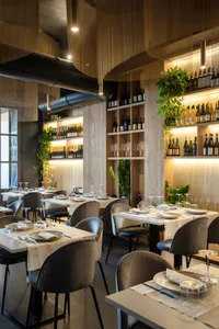 Modern industrial restaurant interior with wooden tables, metal chairs, and glass shelves.