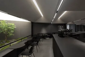 A minimalist coffee shop interior with concrete walls and black furniture.