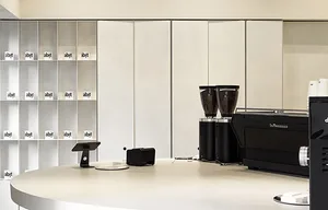 A minimalist coffee shop with a granite countertop, coffee grinding machines, and neatly arranged containers.