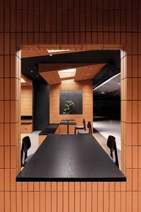 Minimalist restaurant interior with clay tiles, black wooden tables, and a green plant.
