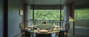 Modern dining room with a glass balustrade, concrete elements, and elegant decor.