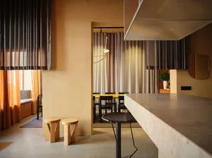 Modern living room with concrete furniture, ambient lighting, and warm tones.