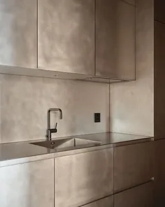 A modern, minimalist kitchen with metallic cabinets and a sleek, integrated sink.