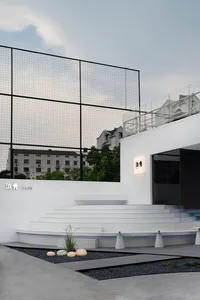Outdoor modern public space with concrete steps, black gravel, and a black fence.