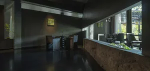 Modern restaurant interior with black concrete, industrial fixtures, and minimalist design.