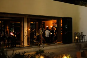People enjoying drinks in a modern restaurant with concrete and glass elements.