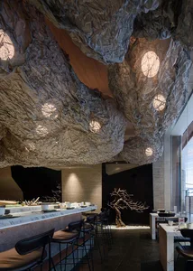 Modern restaurant interior with textured paper ceiling and tree-like structure.