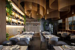 Modern restaurant interior with white tables, glass shelves, and wooden accents.