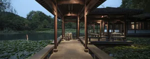 戶外座位區擺放木桌椅，眺望寧靜湖景，四周綠意盎然。