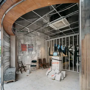 A storefront featuring industrial design elements with concrete walls and a glass partition, including a television on a conc