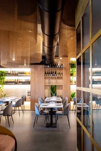 A modern restaurant interior with smooth wood, glass, and metal elements