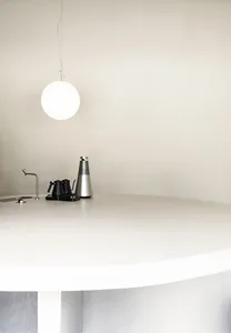 A minimalist kitchen counter featuring a white countertop and a single black kettle.