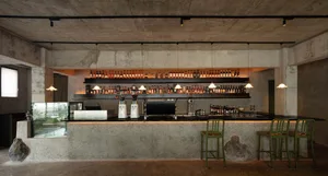 An industrial-style bar with a concrete counter and shelves filled with bottles of alcohol.