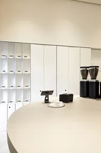 A minimalist café counter with concrete tiles and a sleek, curved white surface.