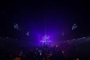 Crowded event space with purple lighting and decorative elements.