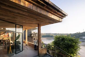 Industrial-style architecture featuring a wooden deck overlooking a river.