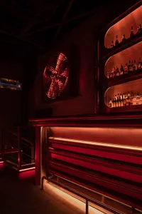 A dimly lit industrial-style bar with metal countertops and shelves filled with bottles.