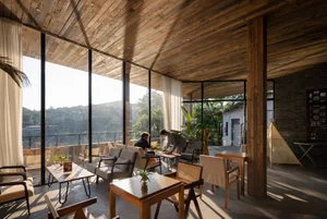 Industrial-style restaurant interior with wooden tables and chairs.