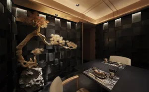 A sleek, metallic and black restaurant interior with a bonsai tree, minimalist table setting, and modern design elements.