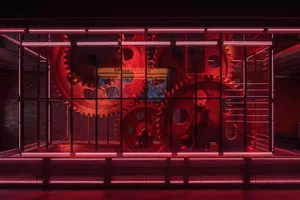 A modern art installation featuring rotating metal gears and neon lighting.