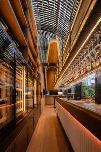 A modern bar with glass, wood, and metal elements.