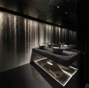 A modern bathroom with glass and stone materials.