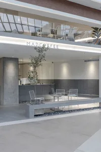 Modern coffee shop interior with minimalist design, featuring concrete and glass materials, and a sleek seating area with whi